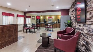 A hotel lobby with a reception desk, seating area, and a kitchenette in the background. - Red Roof Inn Conroe North - Willis (Willis)