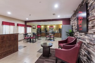 Un vestíbulo de hotel con una recepción, una zona de estar y una kitchenette al fondo.