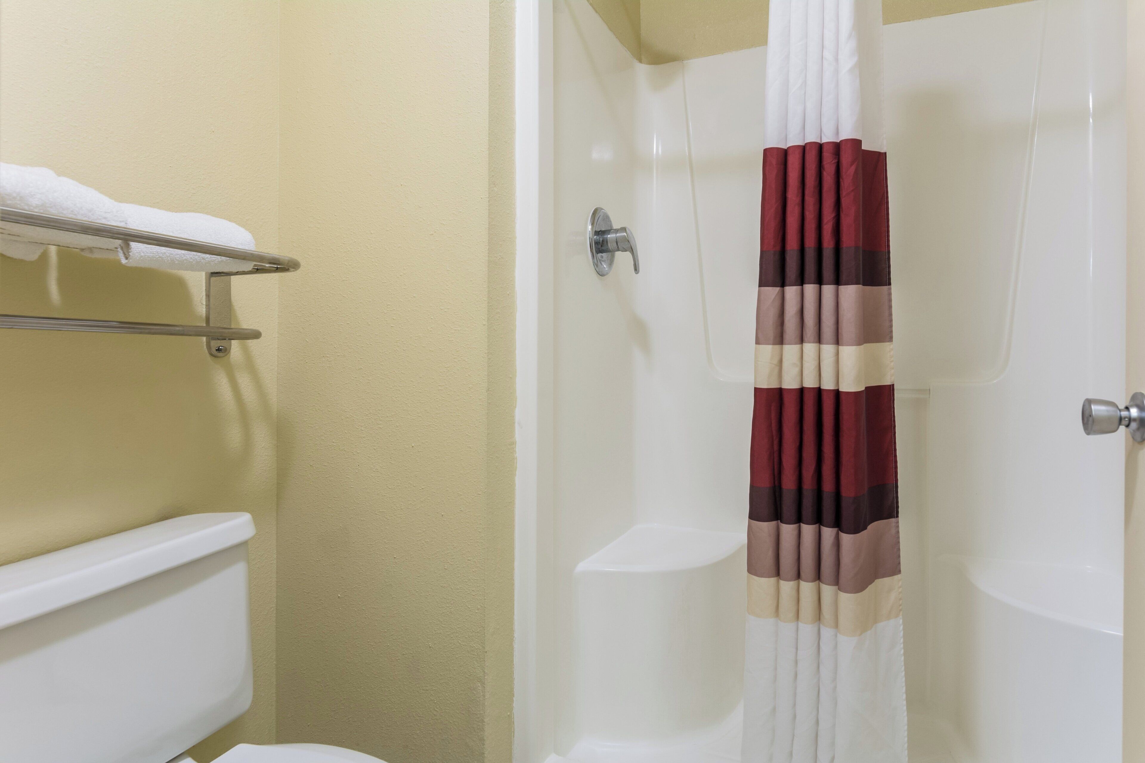 A bathroom with a toilet, a towel rack, a shower curtain, and a bathtub.