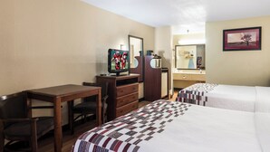 Una habitación de hotel con dos camas, un escritorio, un televisor, un aparador y un espejo.