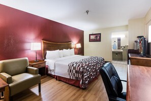 A hotel room with a bed, a desk, a chair, a nightstand, and a mirror. - Red Roof Inn Conroe North - Willis (Willis)