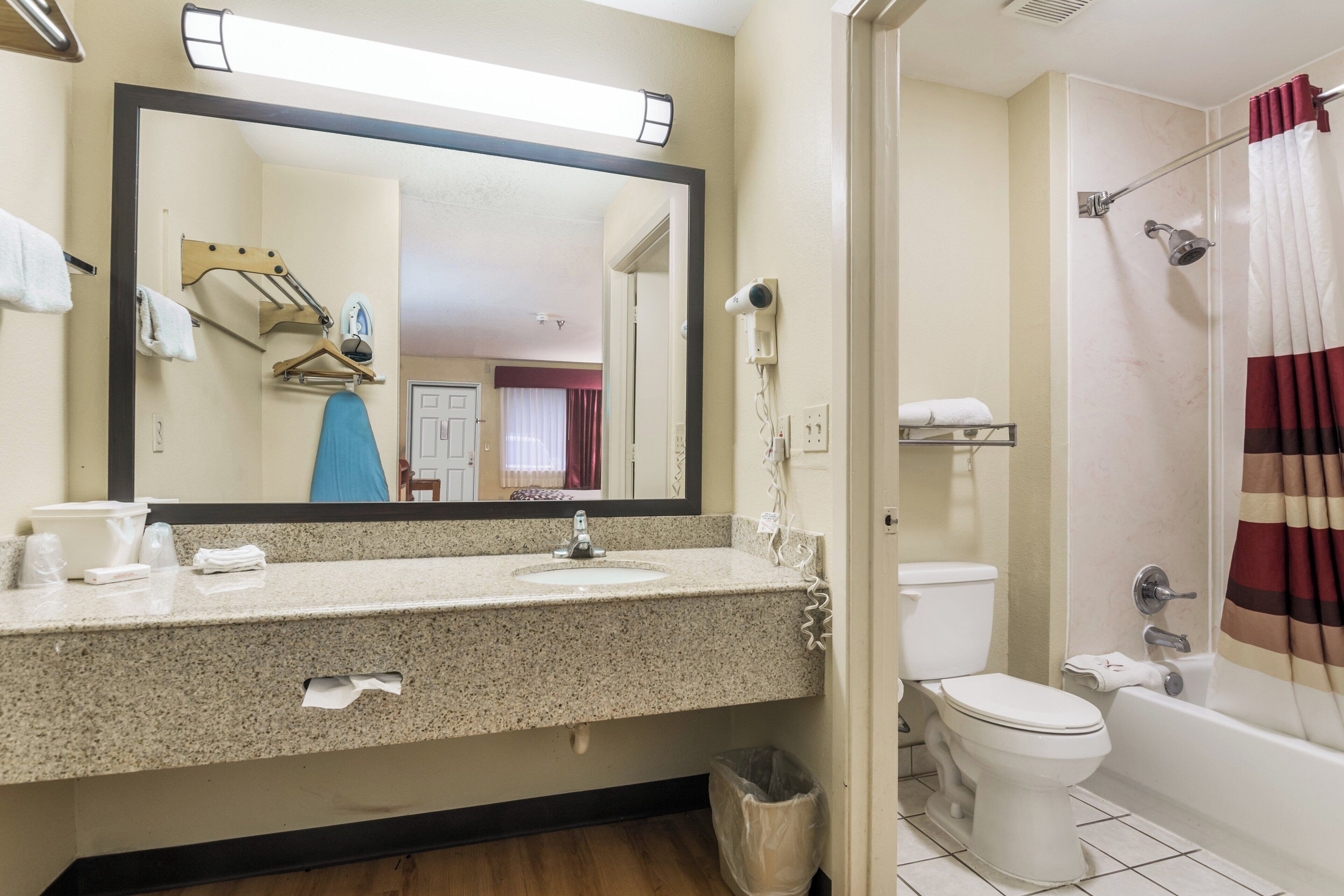 A bathroom with a sink, mirror, toilet, and shower.