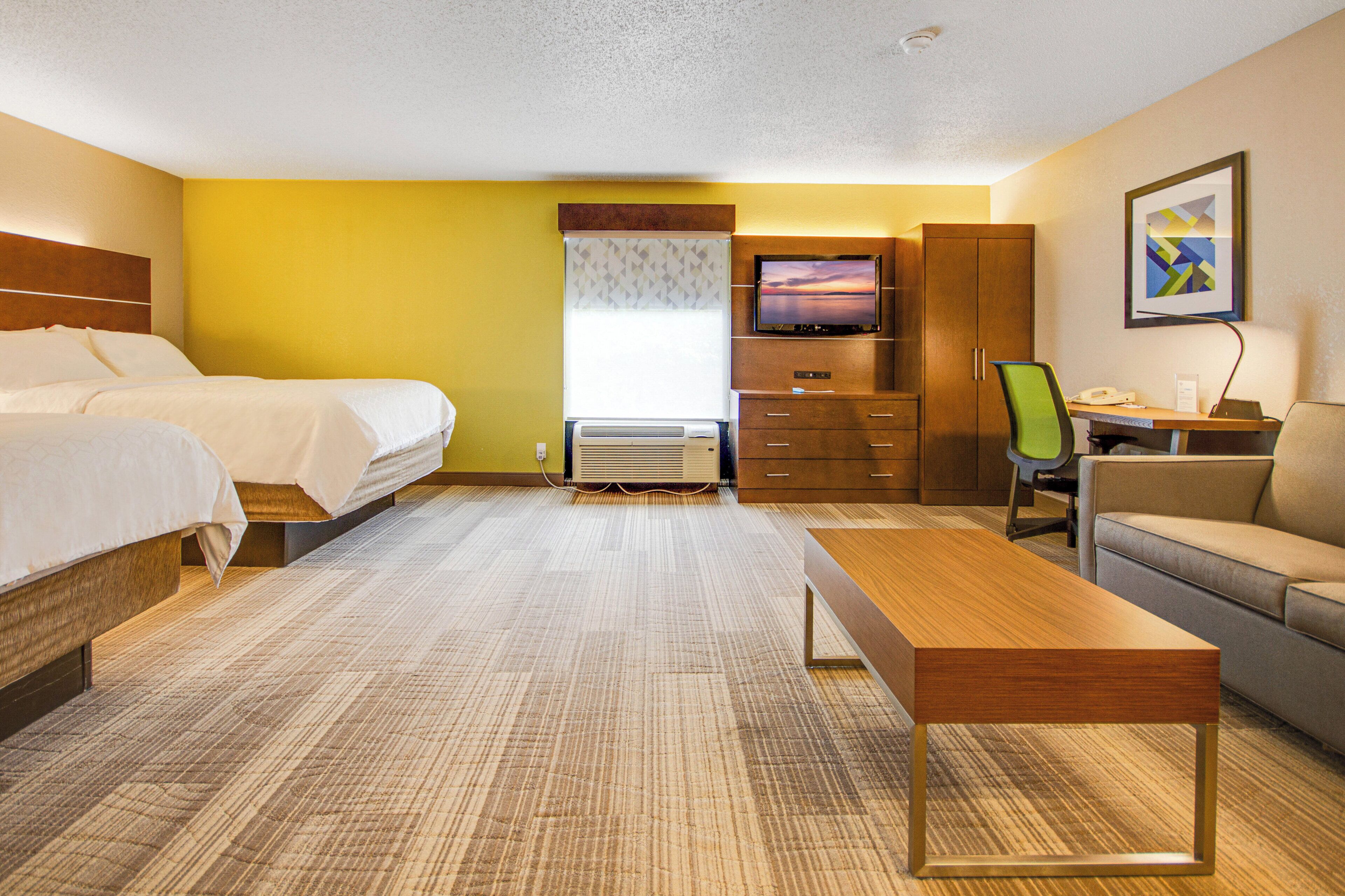 Ein Hotelzimmer mit einem Bett, einem Schreibtisch, einem Sessel, einem Fernseher und einer Couch.
