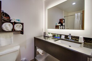 Een badkamer met toilet, wastafel, spiegel en een handdoekrek met handdoeken.