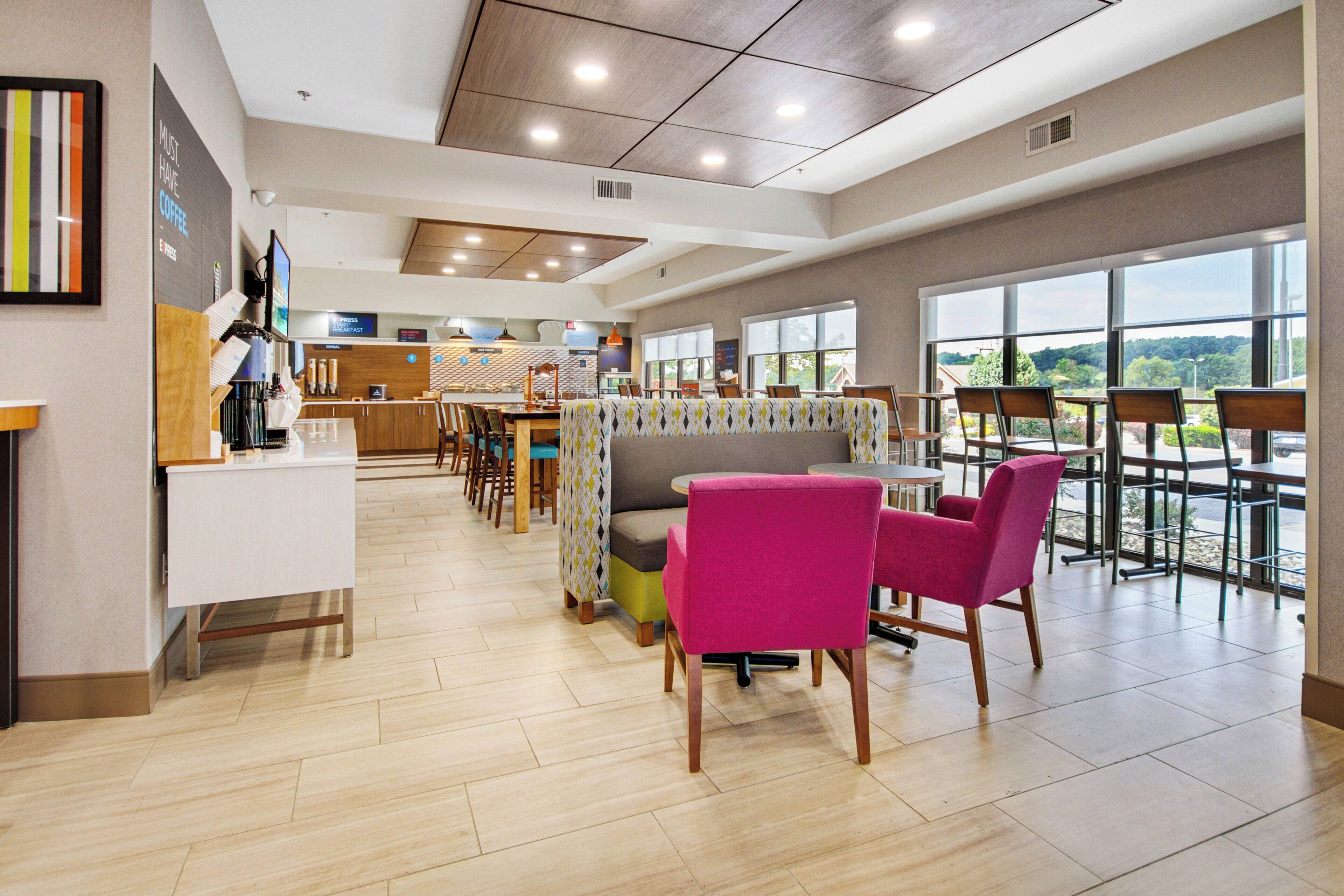 A modern dining area with a breakfast bar, seating arrangements, and large windows offering a view.