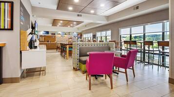 A modern dining area with a breakfast bar, seating arrangements, and large windows offering a view.