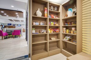 Un área de almacenamiento de alimentos con estantes llenos de diversos aperitivos y bebidas.