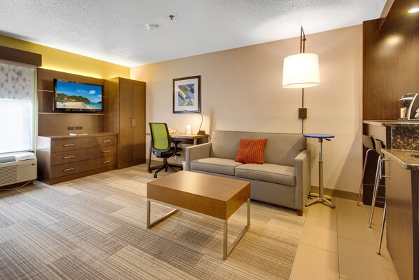 Een moderne hotelkamer met een flatscreen televisie, een bank, een salontafel, een bureau en een lamp.