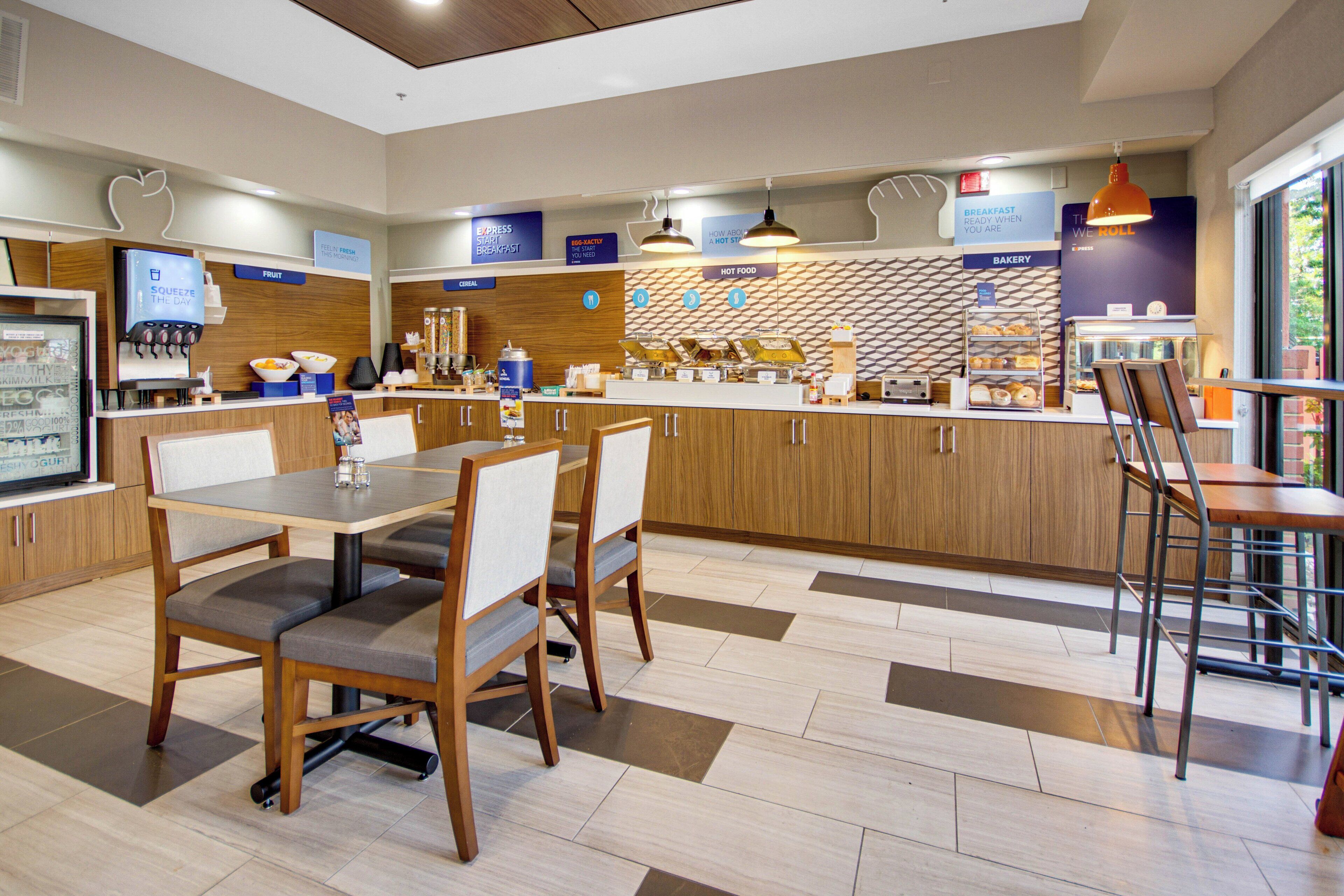 A modern breakfast area with a counter, seating, and a variety of food options.