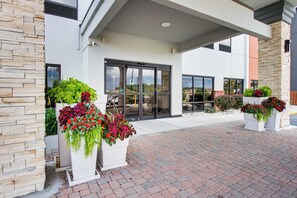 A building entrance with a covered walkway, stone facade, and large windows.