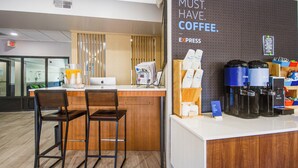 Una zona de cafè amb un cartell que diu 'MUST HAVE COFFEE'. Hi ha tamborets, una màquina de cafè i una exposició de tasses de cafè.