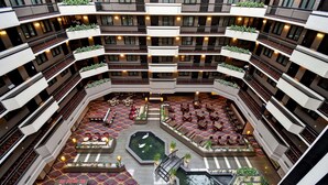 A multi-level atrium with a central courtyard, outdoor seating areas, and multiple balconies with plants. - Embassy Suites by Hilton Dulles Airport (Herndon)