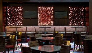 Un restaurant avec des banquettes et des tables, dont les murs sont décorés de motifs et le sol recouvert d’une moquette.