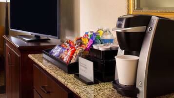 Habitación de hotel con cafetera, refrigerios y televisor.