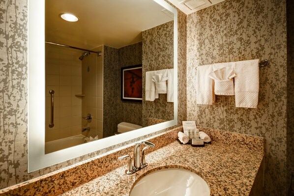 Un baño con un espejo grande, un lavamanos y una ducha.