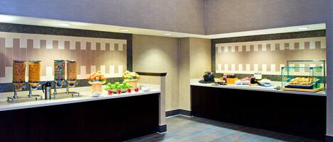 A modern breakfast bar with a variety of food items and a coffee station.