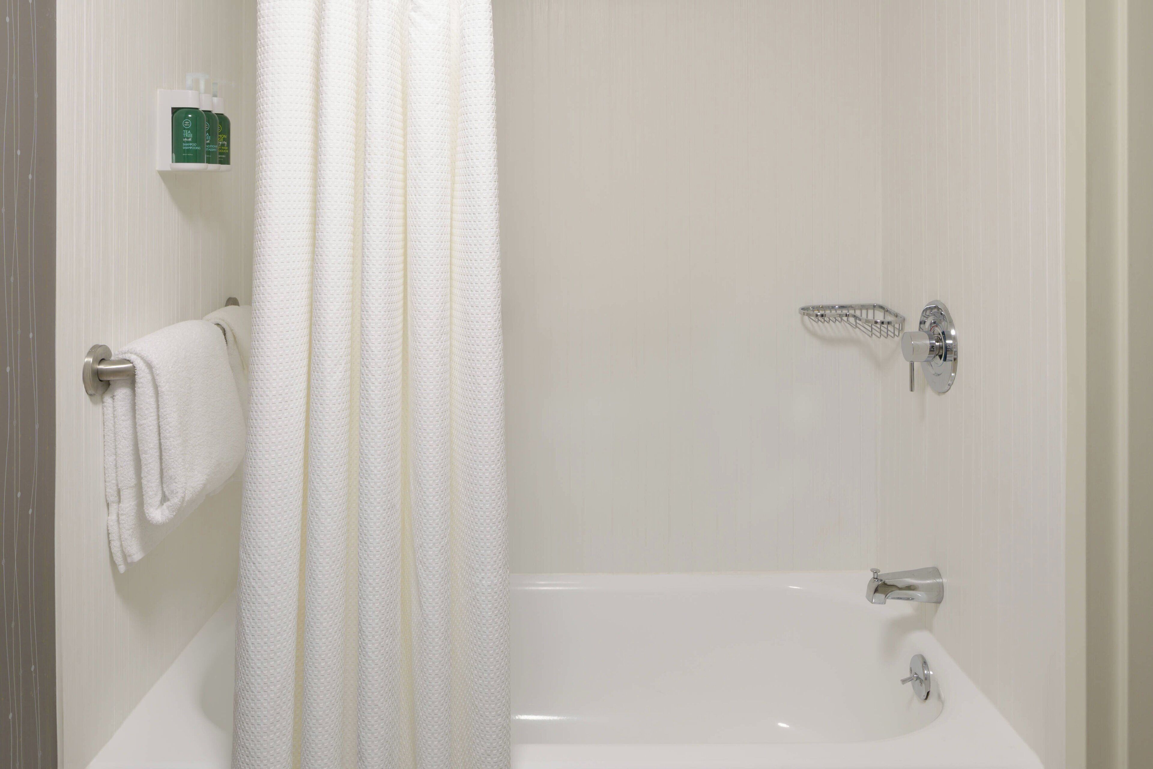 A bathroom with a bathtub, a shower curtain, and a towel rack.