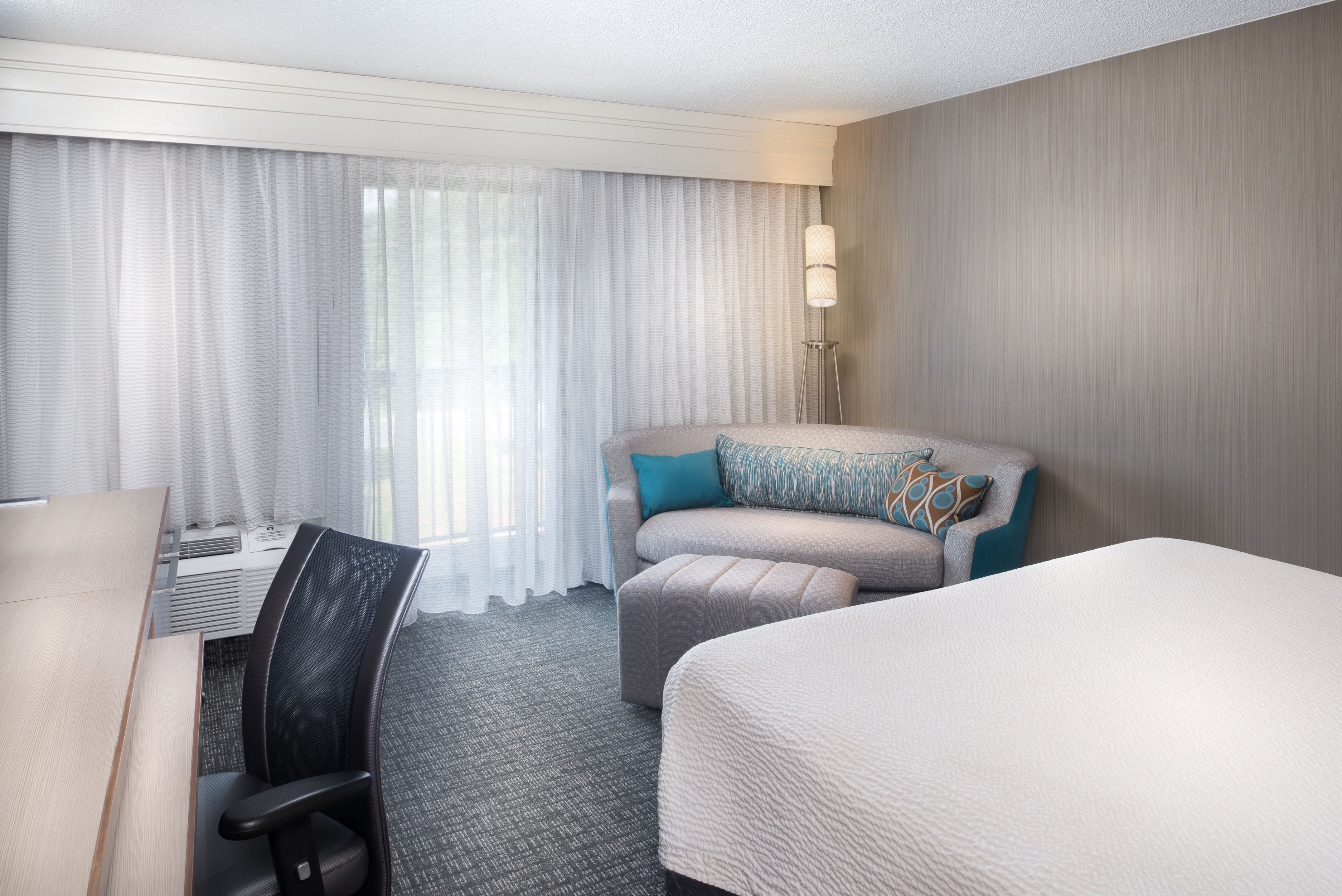 Una habitación de hotel con cama, sofá, escritorio y silla.