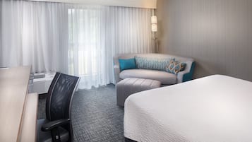Hotellihuone, jossa on sänky, sohva, työpöytä ja tuoli.