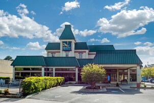 Un hotel con techo verde y un letrero que dice Quality Inn & Suites.