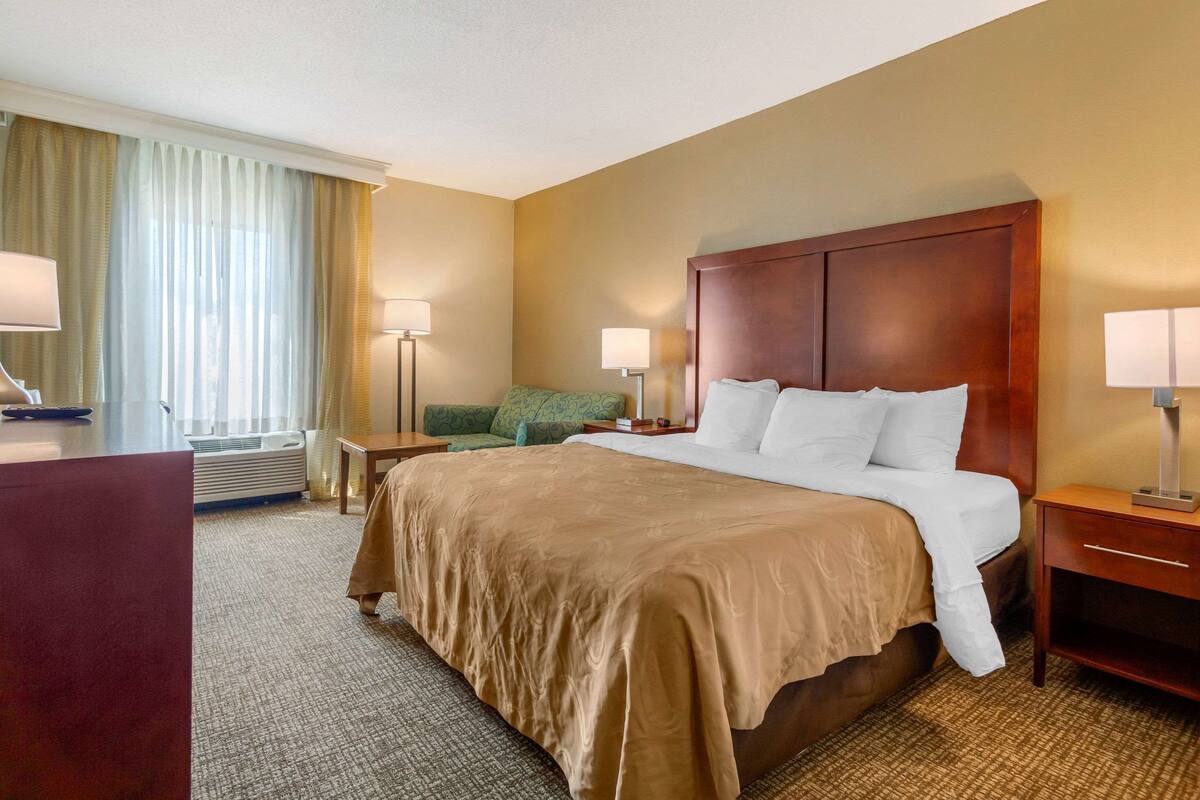 A hotel room with a large bed, two bedside tables, a desk, and a chair.