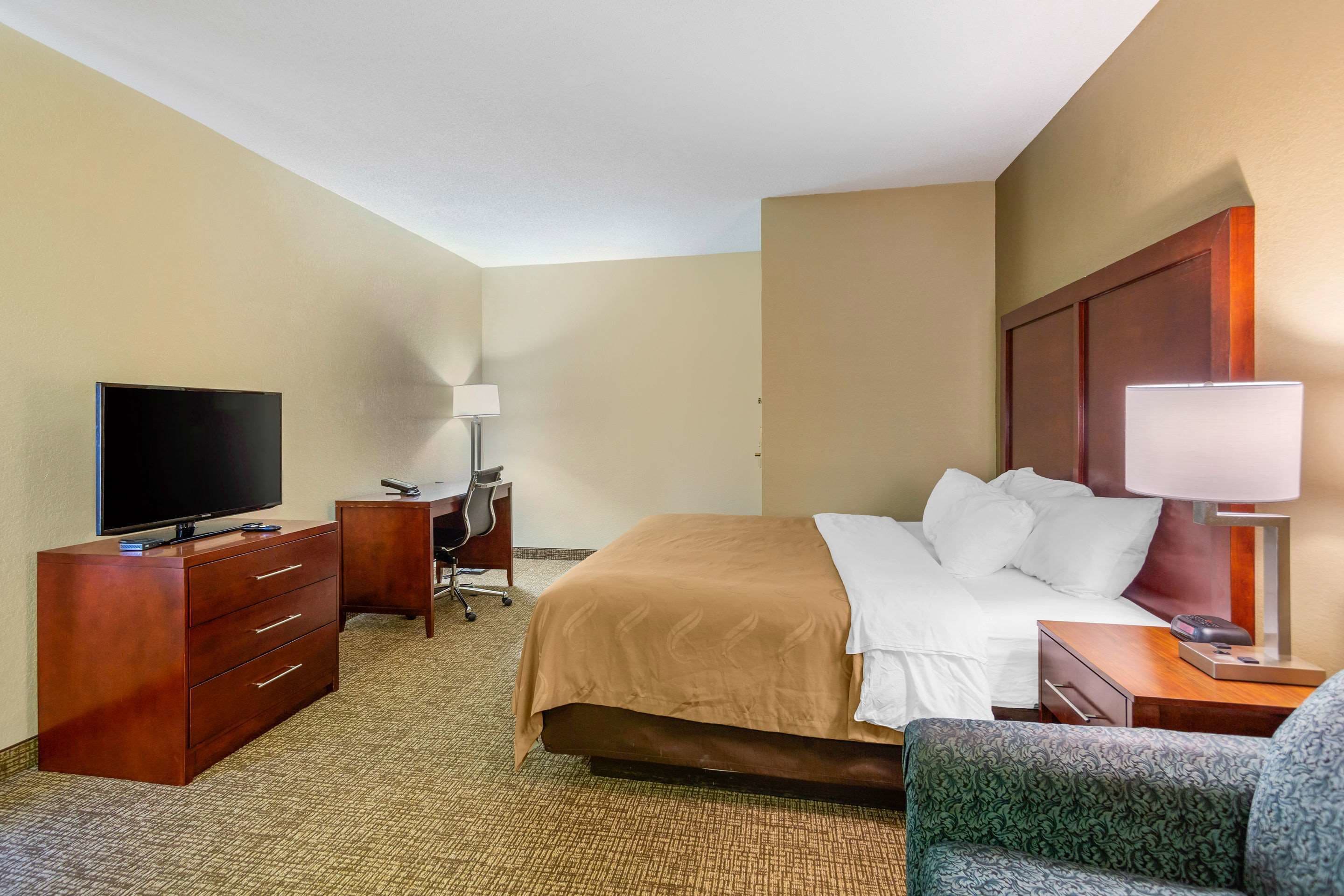 A hotel room with a bed, a desk, a television, and a chair.
