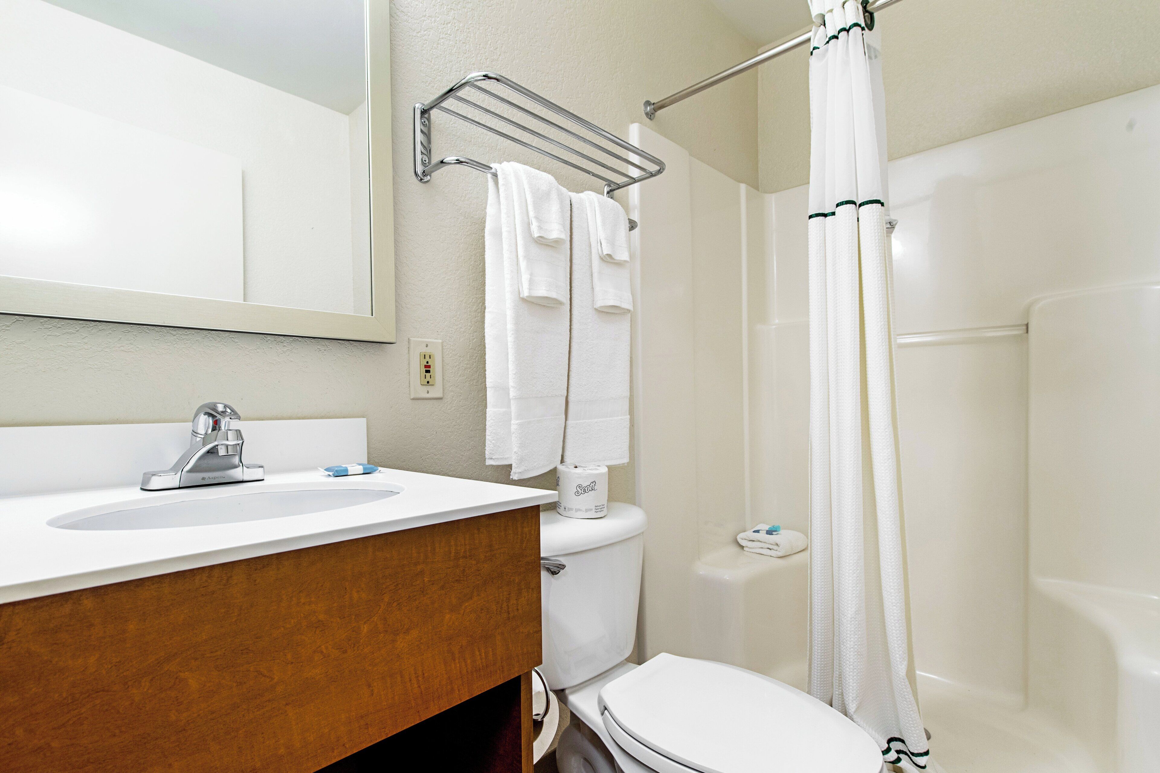 Un baño con lavamanos, inodoro y cortina de ducha blancos.