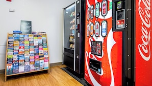 A vending machine with Coca-Cola branding and a display of travel brochures. - HomeTowne Studios by Red Roof Tacoma - Puyallup (Puyallup)