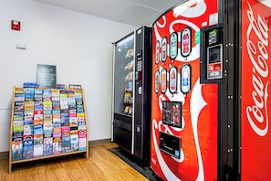 A vending machine with Coca-Cola branding and a display of travel brochures. - HomeTowne Studios by Red Roof Tacoma - Puyallup (Puyallup)