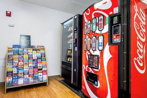 Máquina expendedora con la marca Coca-Cola y una exhibición de folletos turísticos.