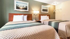 A hotel room with two beds, a nightstand, a lamp, and two framed pictures on the wall. - HomeTowne Studios by Red Roof Tacoma - Puyallup (Puyallup)