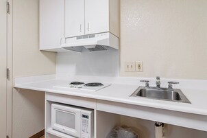 Una cocina con microondas, estufa, lavaplatos y gabinetes blancos.