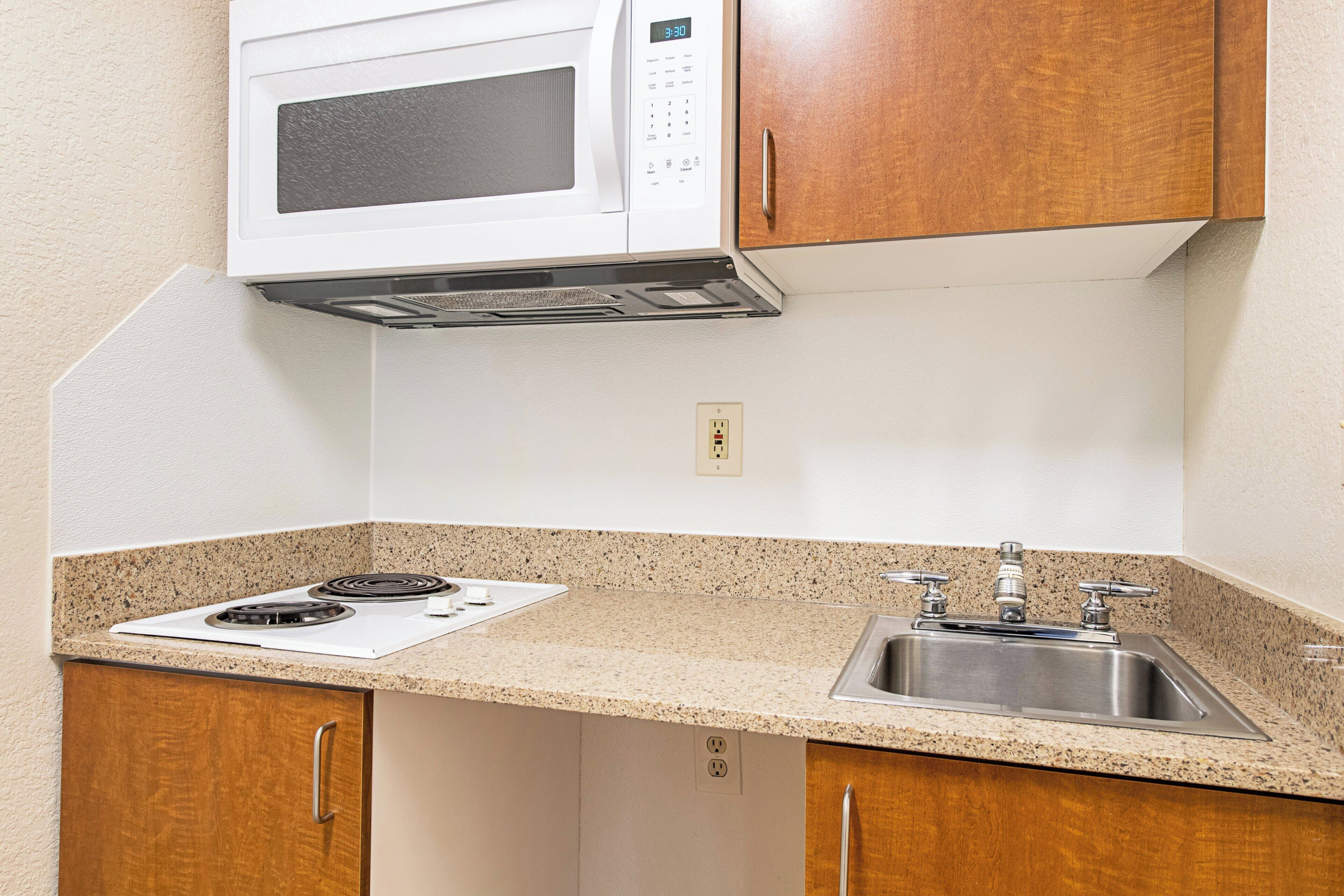 A kitchen with a microwave, stove, and sink.