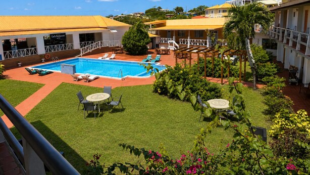 A hotel with a swimming pool, outdoor seating, and a restaurant. - Point Salines Hotel (St. George's)