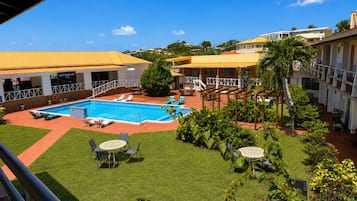 A hotel with a swimming pool, outdoor seating, and a restaurant.