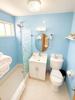 Un baño con ducha, inodoro, lavamanos y espejo.