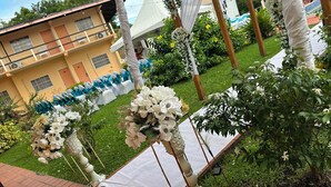 Une décoration de mariage avec des compositions florales blanches et une tente installée dans un jardin.