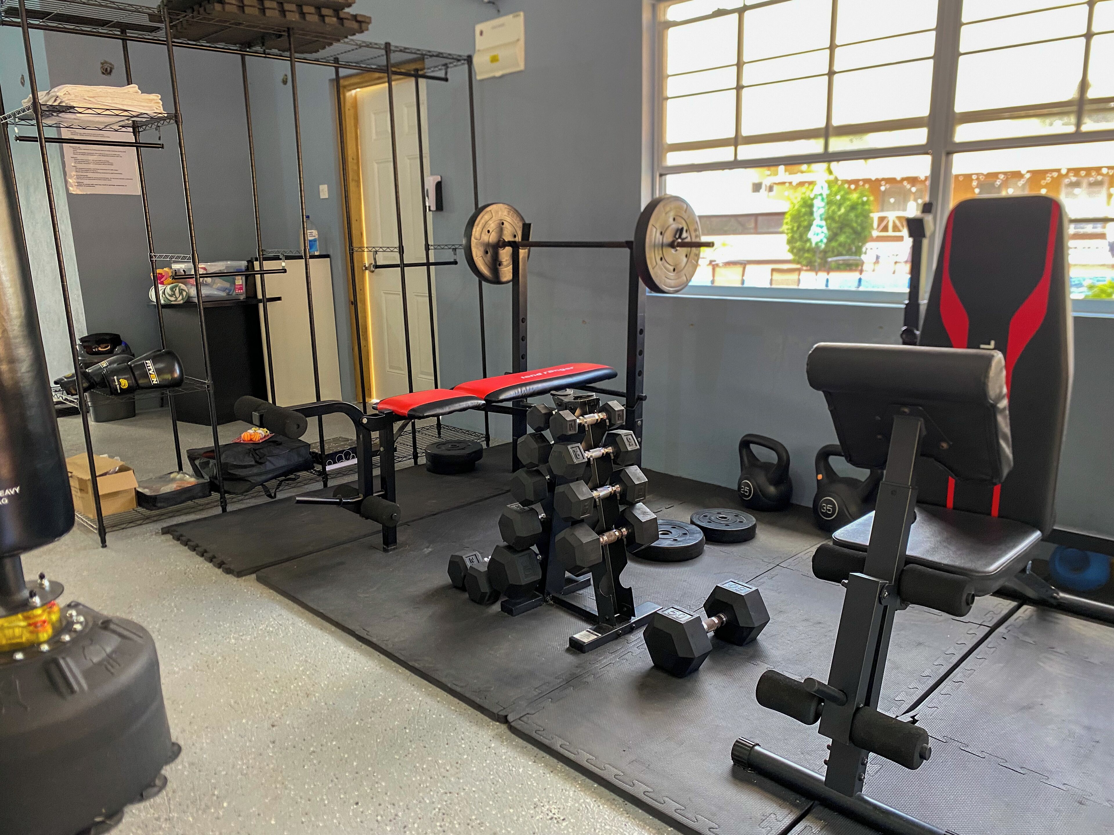 A gym with weightlifting equipment, a bench, and a kettlebell.