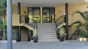 En hotellentrél med en trappa, krukväxter och skyltar som visar vägen till receptionen, konferensrummet och restaurangen.