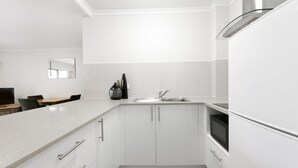 A modern kitchen with white cabinets, a stainless steel sink, and a built-in oven.
