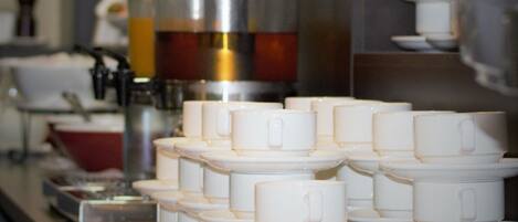 Montaje de bufé con varias estaciones de servicio, que incluye un dispensador de café y una variedad de platos.