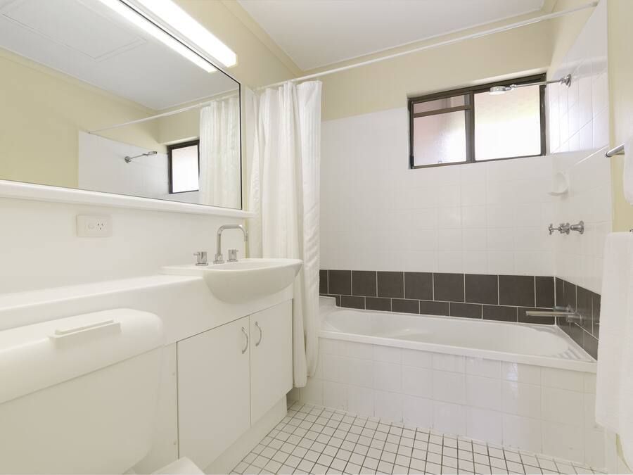 A bathroom with a white sink, mirror, and bathtub.