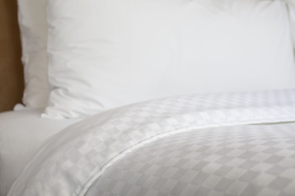 A close-up of a bed with a patterned bedspread and pillows.