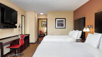 Habitación de hotel con cama, escritorio, silla, televisión y un cuadro en la pared.