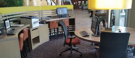 A modern office space with multiple workstations, ergonomic chairs, and a central meeting table.