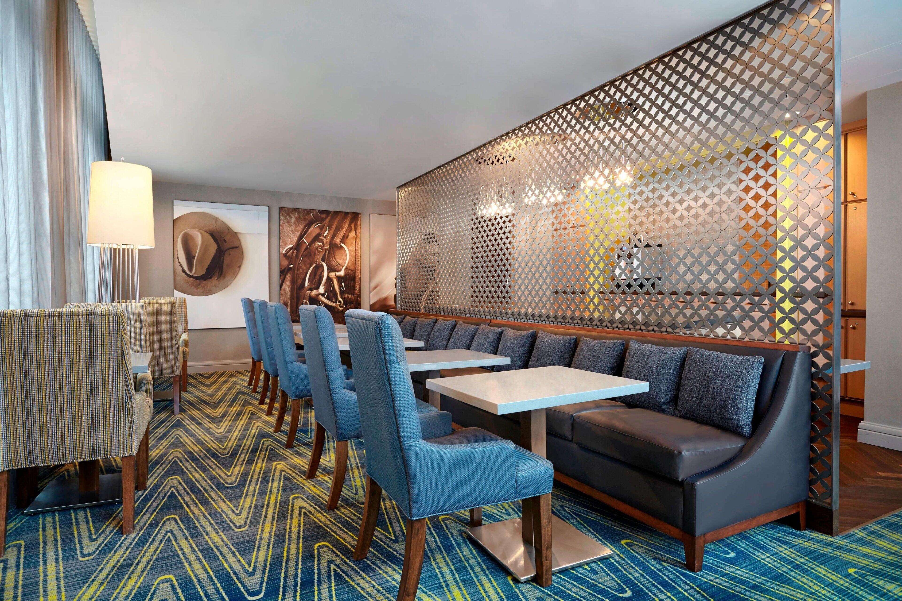 Un espace repas moderne avec des chaises à revêtement bleu, un canapé et un sol à motifs.