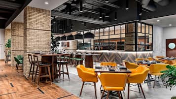 Un restaurante moderno con suelo de madera, paredes de ladrillo y sillas amarillas.