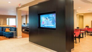 A modern hotel lobby with a large digital screen displaying information, a seating area with sofas and chairs, and a reception desk. - Courtyard by Marriott Livermore (Livermore)