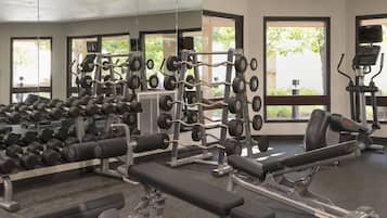 A gym with various weightlifting equipment, benches, and dumbbells.