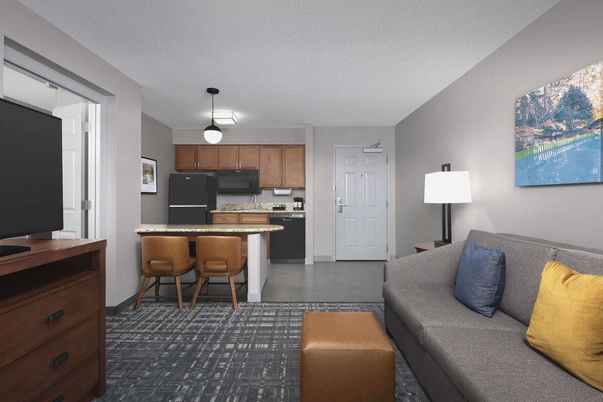 A modern living room with a grey sofa, a coffee table, and a TV stand.